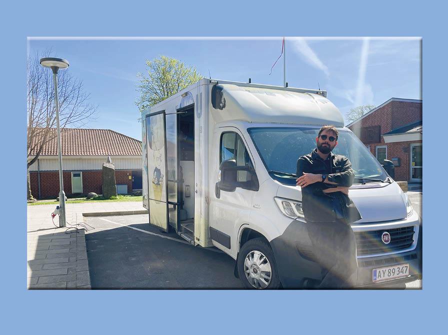 Linus poserer foran bogbussen på en solskinsdag